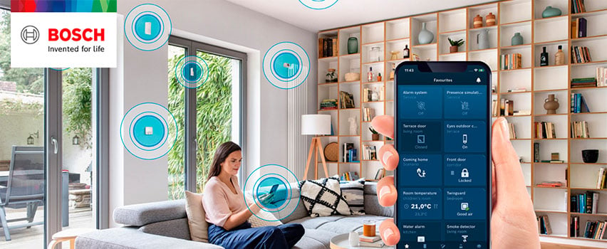 Bosch Smart Home app viser favoritter som alarm, døre, rumtemperatur og røgalarm i smart hjem med kvinde i sofa