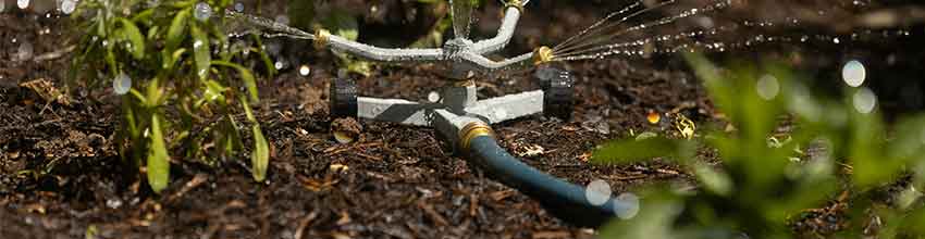 Sprinkler placeret i bed sprøjter vand i tre forskellige retninger.
