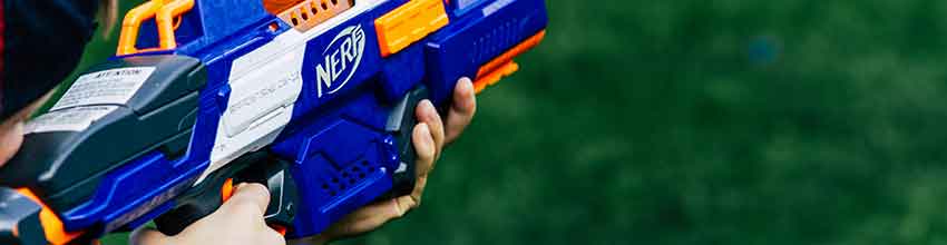 Dreng holder og sigter med en blå og orange Nerf gun.