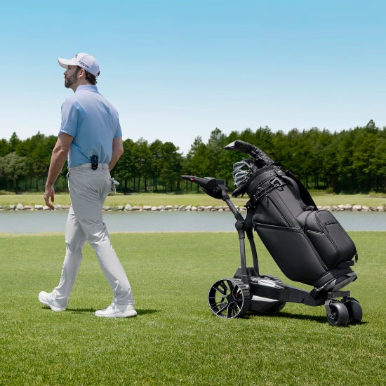 Golfspiller går ved siden af Navee elektrisk golftrolley med golfbag på golfbanen