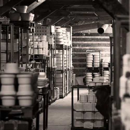 Pillivuyts franske porcelænsfabrik med reoler fyldt med hvide skåle og tallerkener i sort-hvid