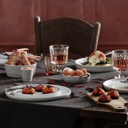 Pillivuyt Toulouse tallerkener med tapas, rejer i skål og rosévin på festbord med grå hørdug