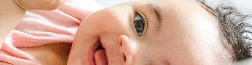 Smilende baby pige i lyserødt, gaveidé til piger der skaber glæde og nærhed.