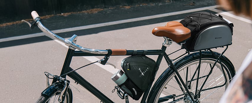 Vintage-cykel med Wozinsky sadeltaske og rammetaske parkeret på solrig gade – cykeltilbehør til touring