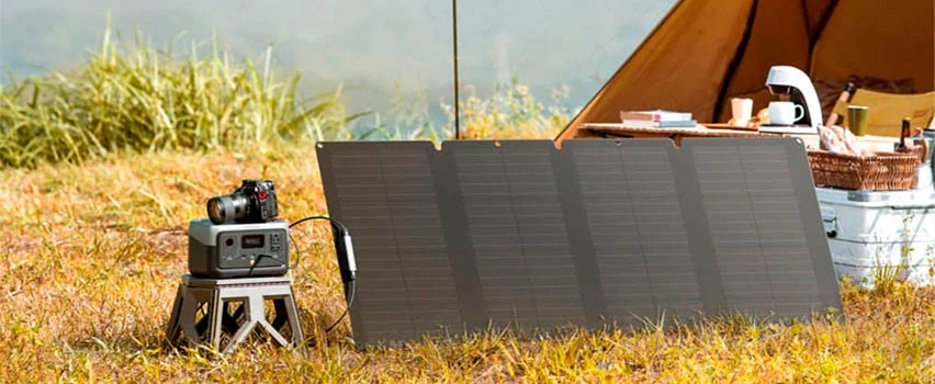 EcoFlow RIVER 2 power station og solpanel opstillet ved telt på græsmark – kompakt off-grid energiløsning til camping