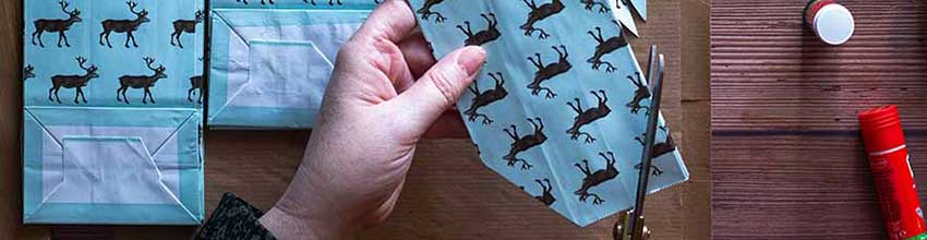 Hænder laver kreativ juleaktivitet med papir og lim, oplagt idé til DIY julelege.